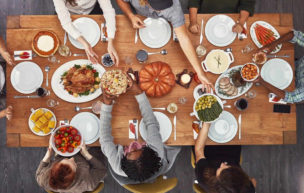 Overhead shot of people passing dishes at a Thanksgiving dinner