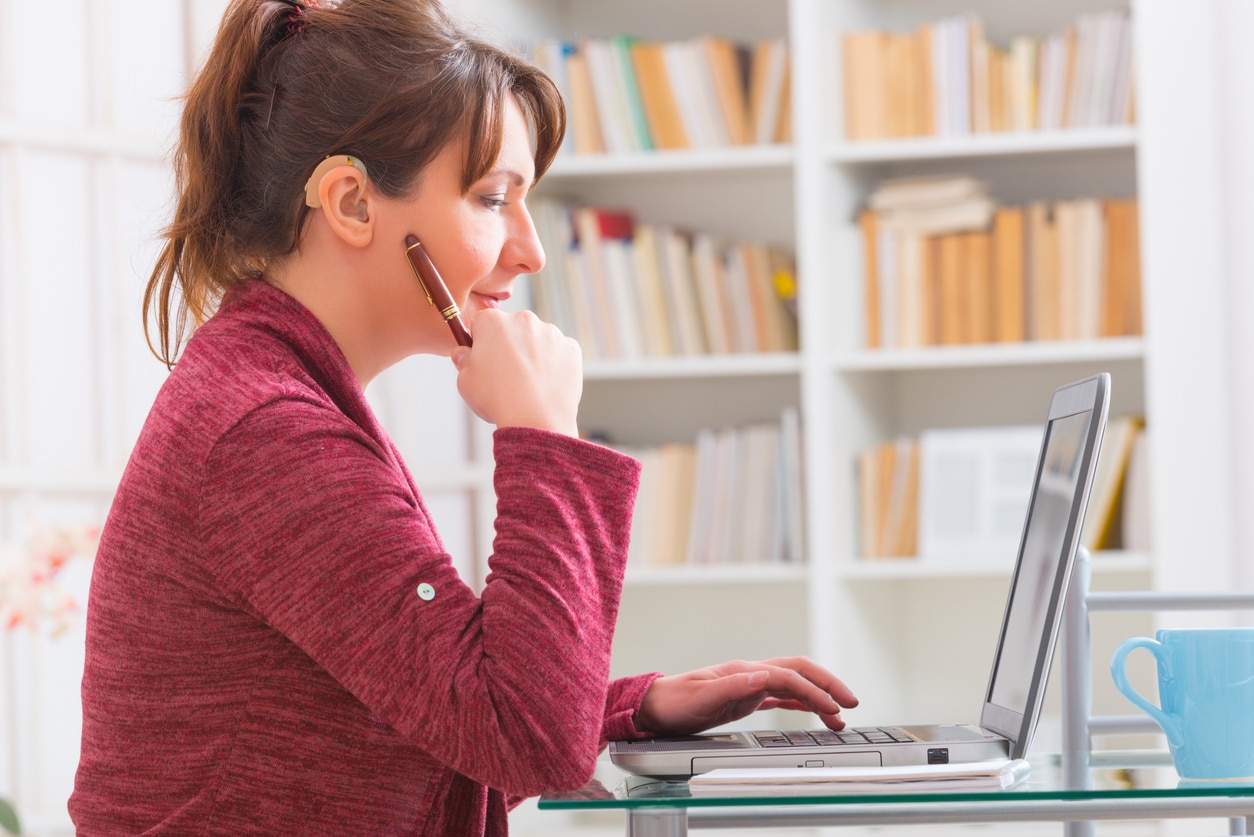 Woman with a hearing aid working on her laptop